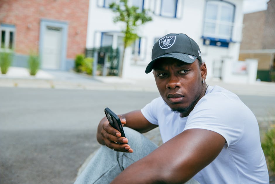 Casual portrait of a young man sitting outdoors in Brussels with his smartphone.