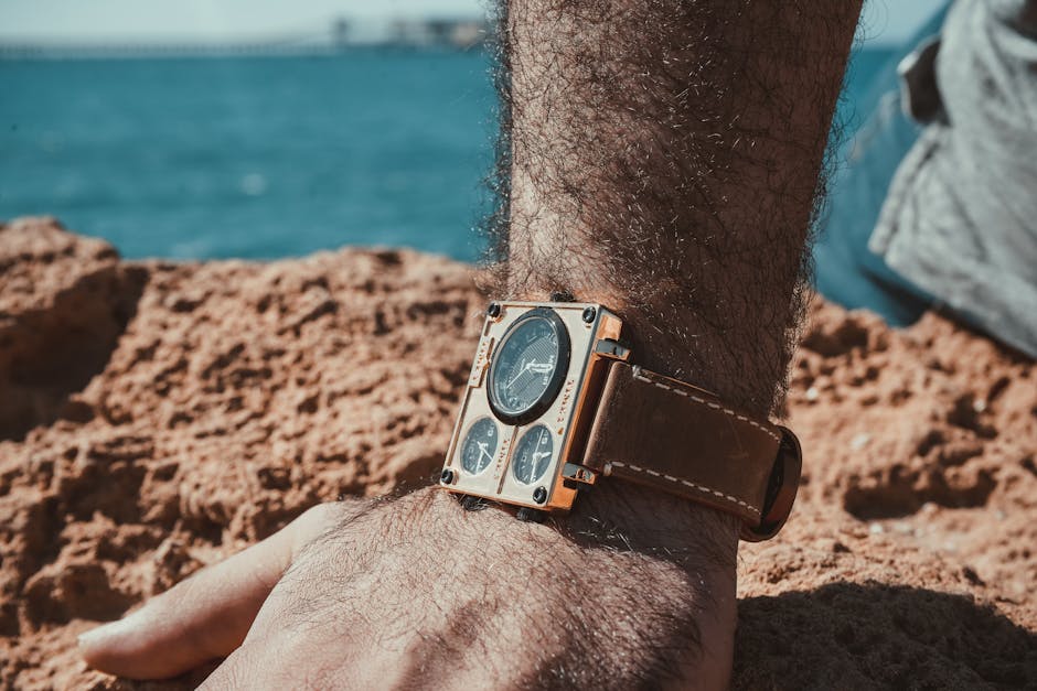Close-up of a wristwatch with a brown leather strap by the beach under sunlight.