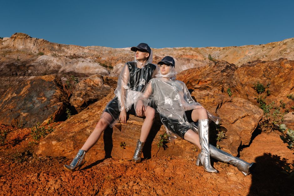 Fashion models in trendy outfits posing on rocky terrain under clear skies.