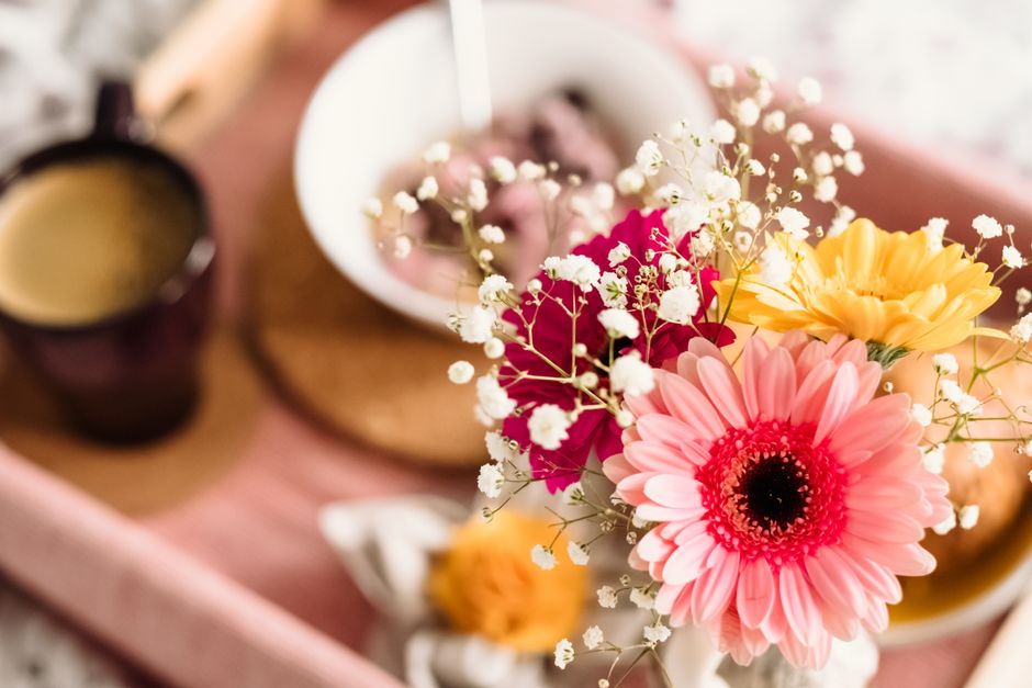 Bright flowers on a serving tray with coffee and food in a cozy setting.