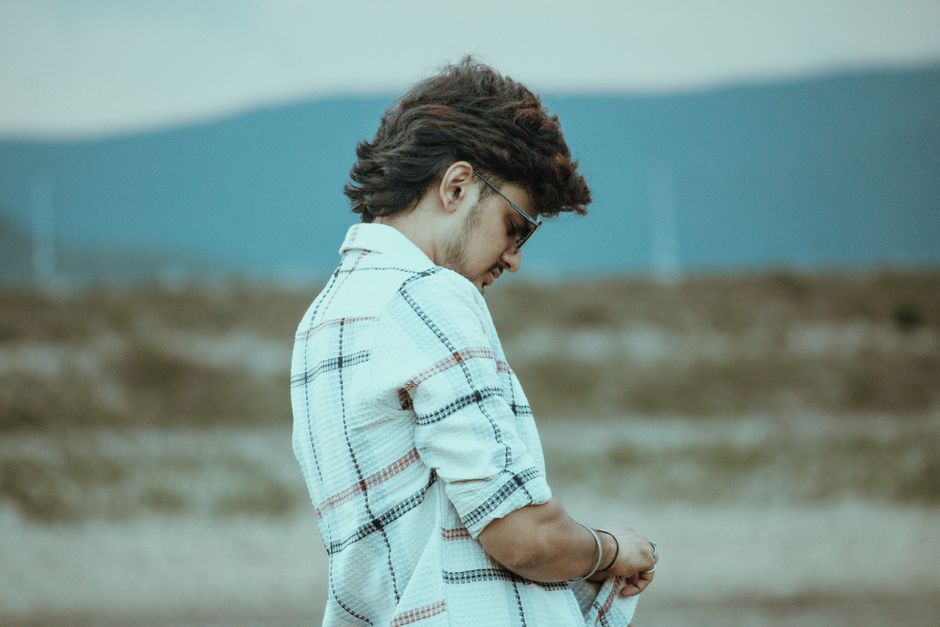 Side view of a man in a plaid shirt standing outdoors in Salem, India.
