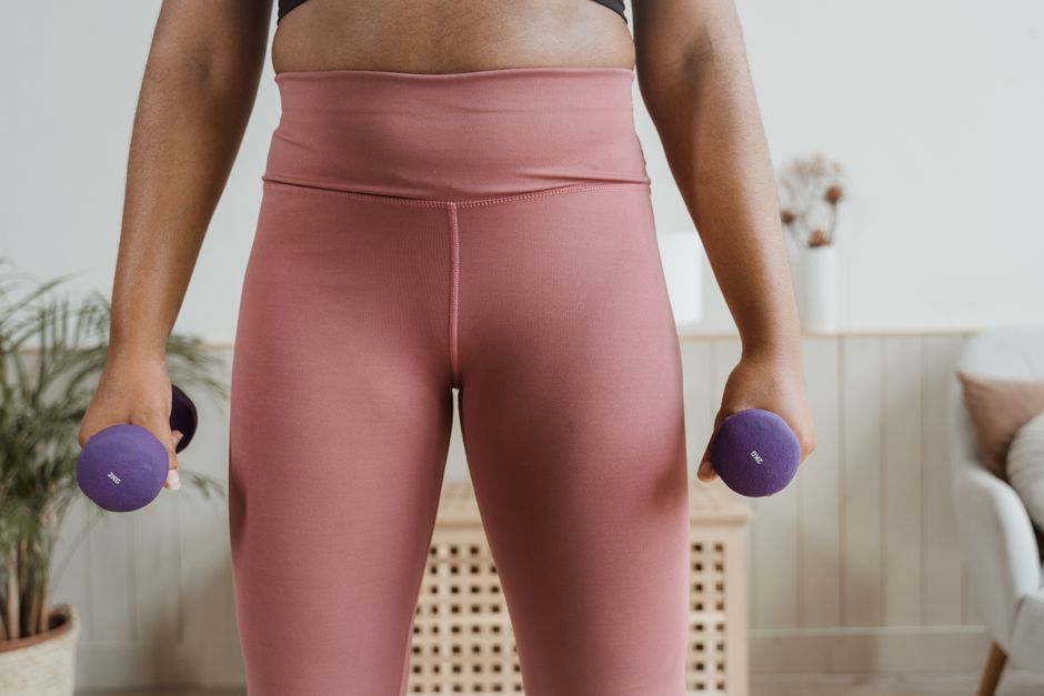 Close-up of a woman holding purple dumbbells, highlighting fitness and healthy lifestyle indoors.