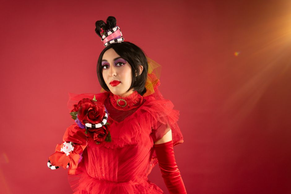 Fashionable cosplay featuring a black wig and red floral costume with dramatic makeup.
