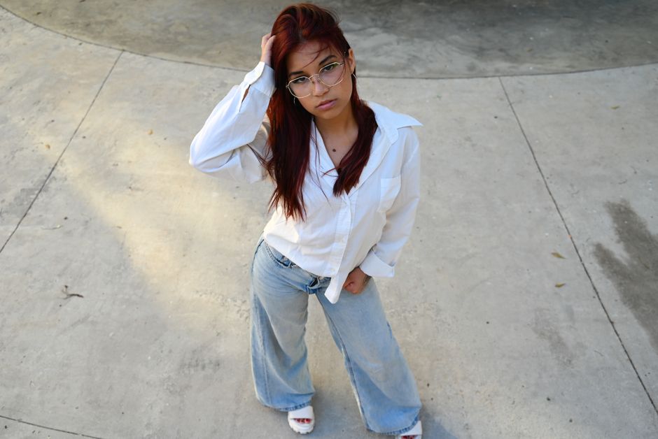 Young woman in casual outfit poses confidently outdoors, showcasing modern fashion and style.