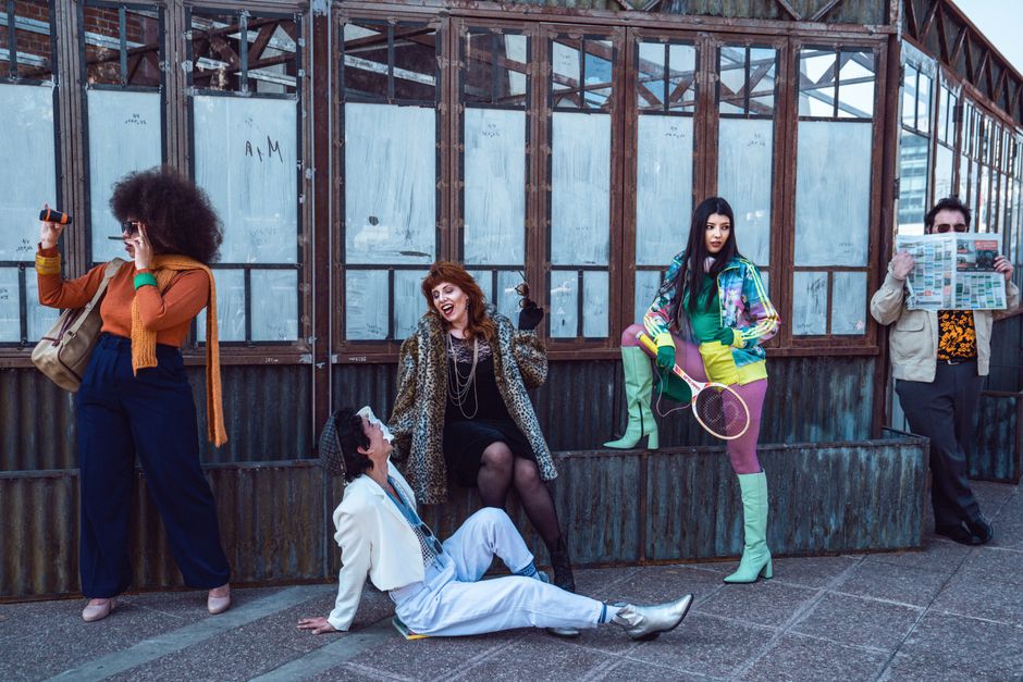 Trendy group of adults posing with urban background, showcasing fashion and fun.