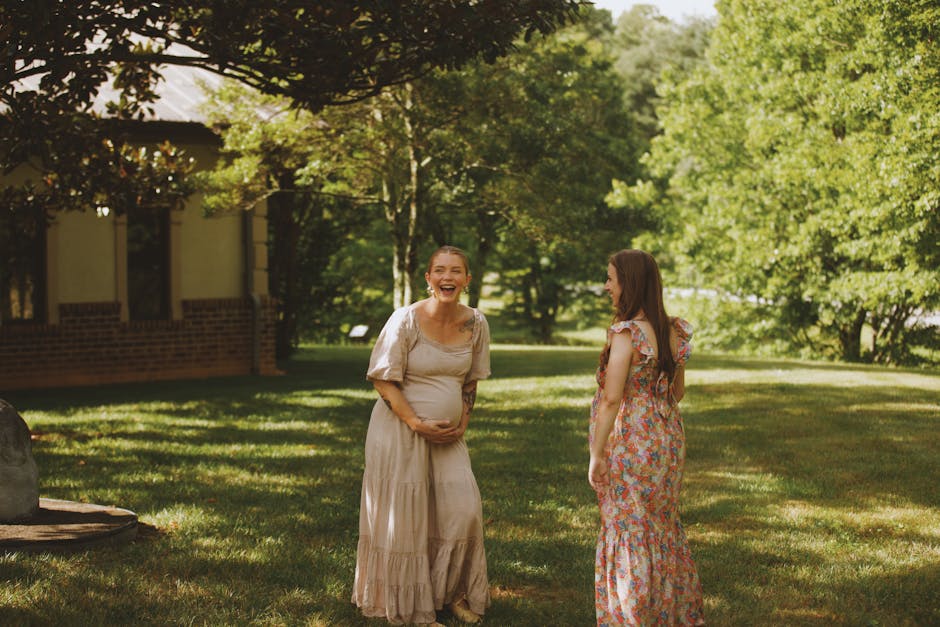 Two expecting mothers enjoying a sunny day in a lush garden setting.
